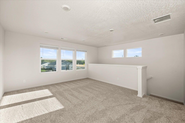 empty room featuring a textured ceiling and light carpet