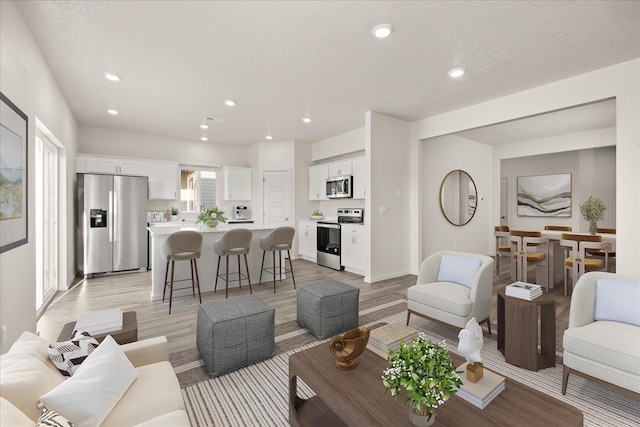 living room with a textured ceiling and light wood-type flooring