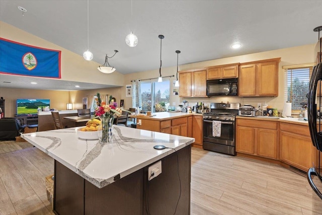 kitchen with a center island, hanging light fixtures, stainless steel gas range, light stone counters, and light hardwood / wood-style floors