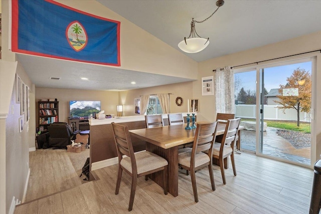 dining area with vaulted ceiling and light hardwood / wood-style flooring