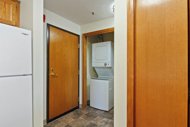 laundry area with a textured ceiling and stacked washer and dryer