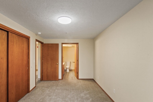 corridor featuring a textured ceiling and light carpet