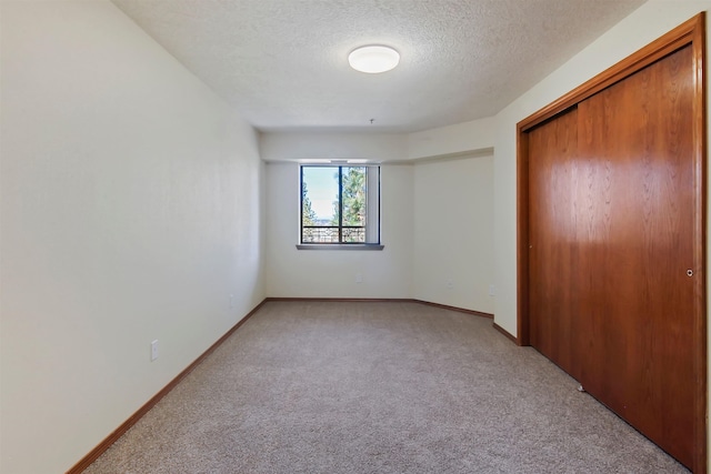 unfurnished bedroom with a closet, light colored carpet, and a textured ceiling