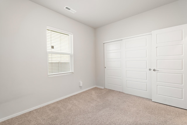 unfurnished bedroom with light carpet and a closet