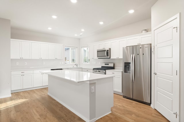 kitchen featuring white cabinetry, a center island, stainless steel appliances, and light hardwood / wood-style flooring