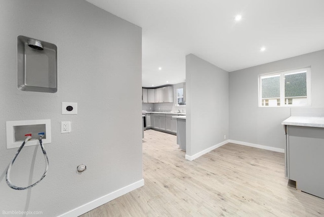 washroom with hookup for an electric dryer, gas dryer hookup, light wood-type flooring, and hookup for a washing machine