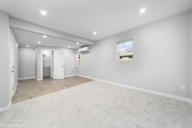 basement featuring light hardwood / wood-style flooring and a wall mounted AC