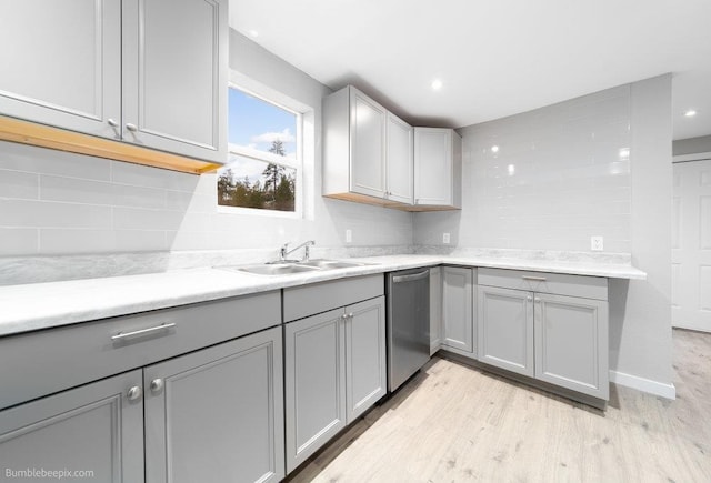 kitchen with dishwasher, sink, gray cabinets, light wood-type flooring, and tasteful backsplash