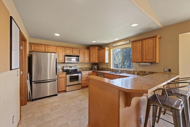 kitchen featuring sink, kitchen peninsula, stainless steel appliances, and a breakfast bar area