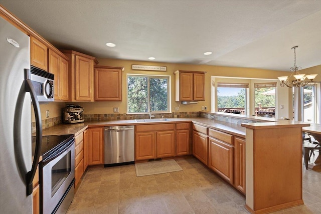 kitchen with decorative light fixtures, kitchen peninsula, stainless steel appliances, and a chandelier