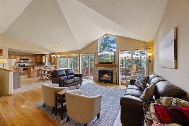 living room with a fireplace, high vaulted ceiling, light hardwood / wood-style flooring, and a notable chandelier