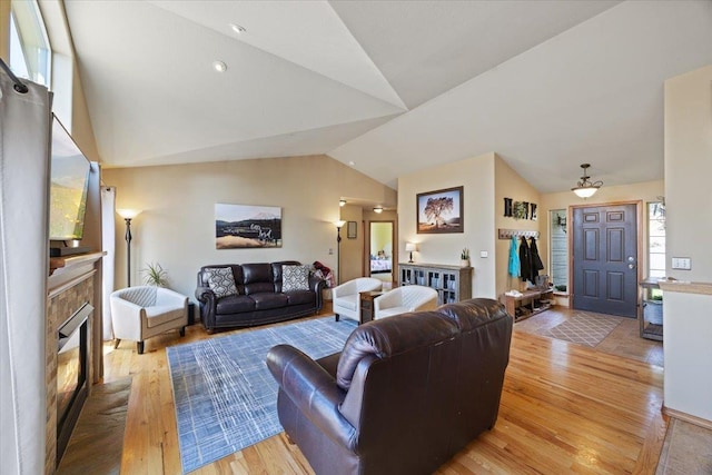 living room featuring a fireplace, light hardwood / wood-style flooring, and lofted ceiling