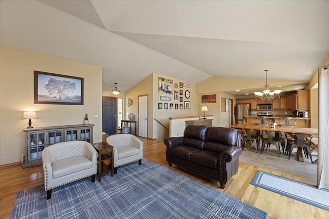 living room with light hardwood / wood-style floors, lofted ceiling, and an inviting chandelier