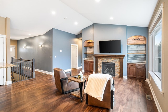 living room with a stone fireplace, dark wood-type flooring, and vaulted ceiling