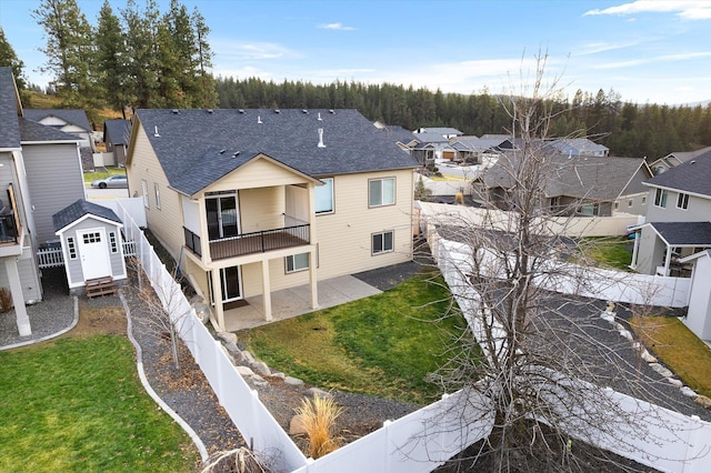 rear view of house featuring a yard and a balcony