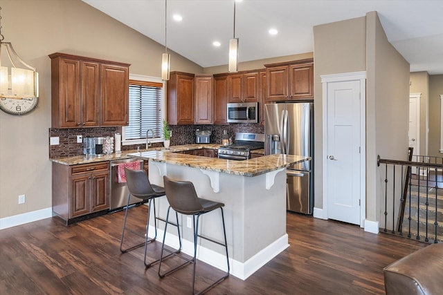 kitchen featuring light stone countertops, a center island, pendant lighting, vaulted ceiling, and appliances with stainless steel finishes