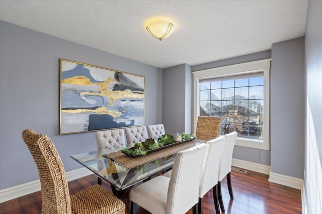 dining room with a textured ceiling and dark hardwood / wood-style floors