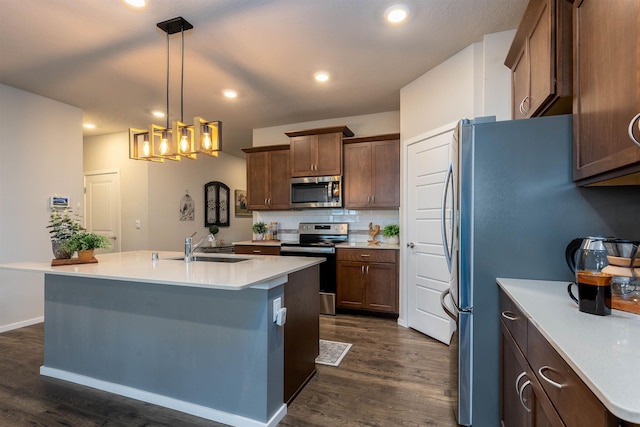 kitchen featuring a kitchen island with sink, dark wood-type flooring, pendant lighting, and appliances with stainless steel finishes