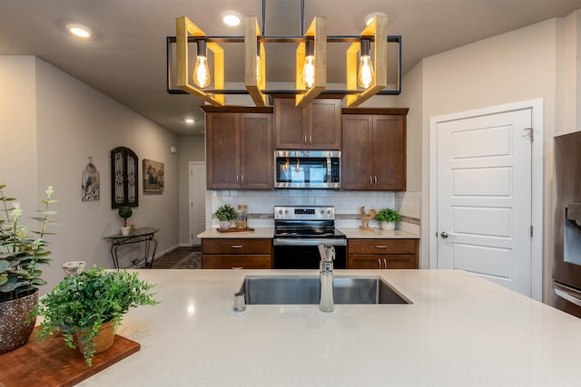 kitchen with backsplash, decorative light fixtures, sink, and appliances with stainless steel finishes