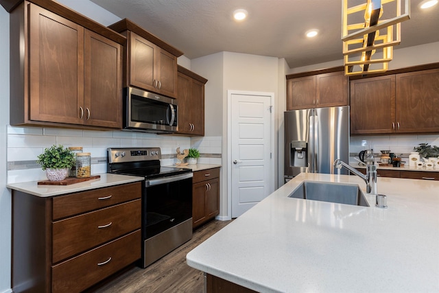 kitchen with pendant lighting, sink, tasteful backsplash, dark hardwood / wood-style flooring, and stainless steel appliances