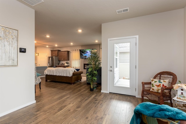 bedroom featuring stainless steel fridge and dark wood-type flooring