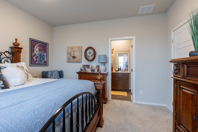 bedroom with ensuite bathroom and light carpet