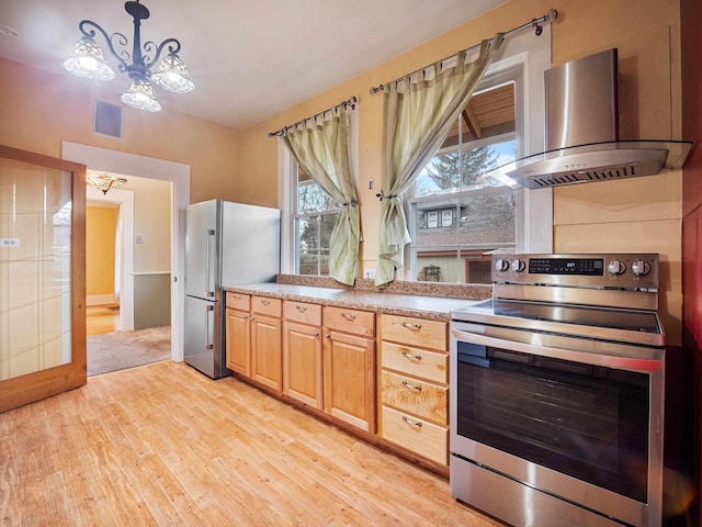 kitchen featuring decorative light fixtures, appliances with stainless steel finishes, a notable chandelier, light hardwood / wood-style floors, and extractor fan