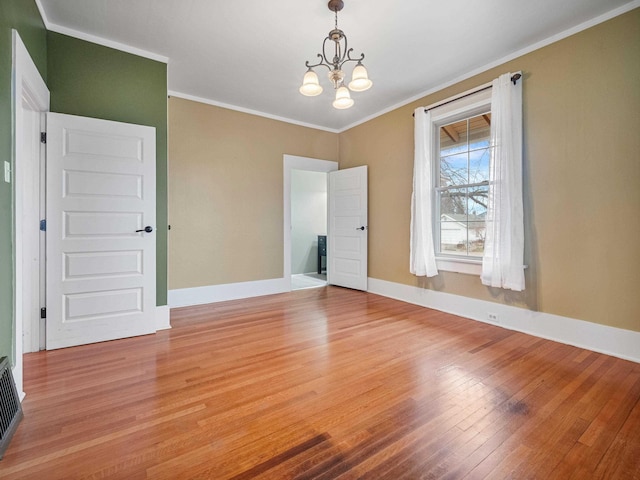 unfurnished room with crown molding, light wood-type flooring, and an inviting chandelier