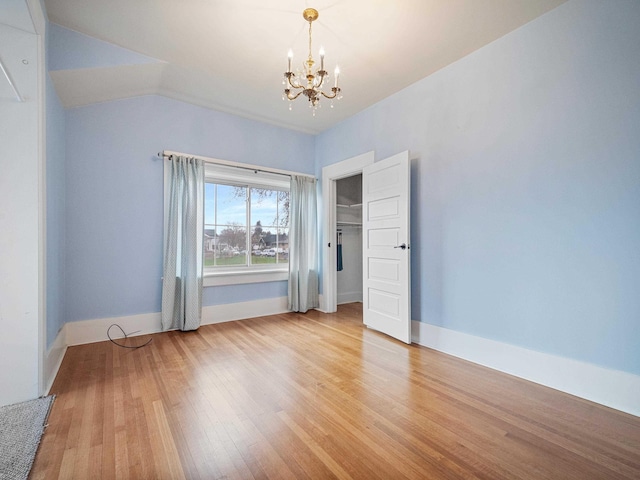 unfurnished bedroom with vaulted ceiling, light hardwood / wood-style flooring, an inviting chandelier, and a closet