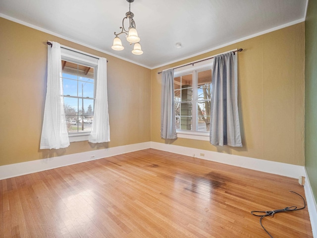 spare room with crown molding, wood-type flooring, and a notable chandelier