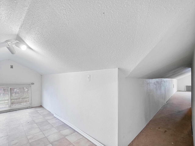 additional living space featuring a textured ceiling and lofted ceiling