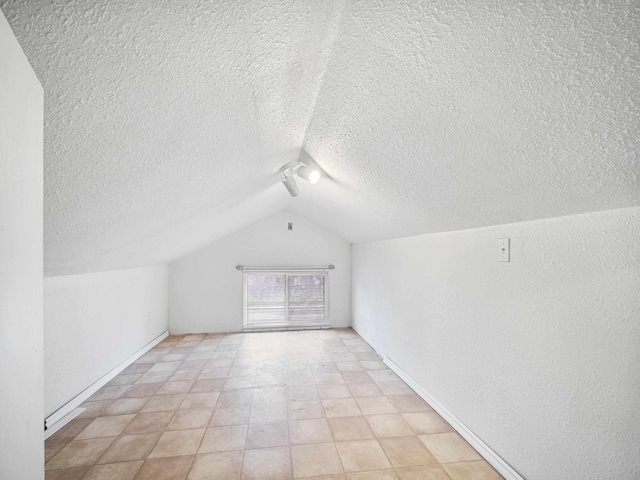 additional living space with a textured ceiling and vaulted ceiling