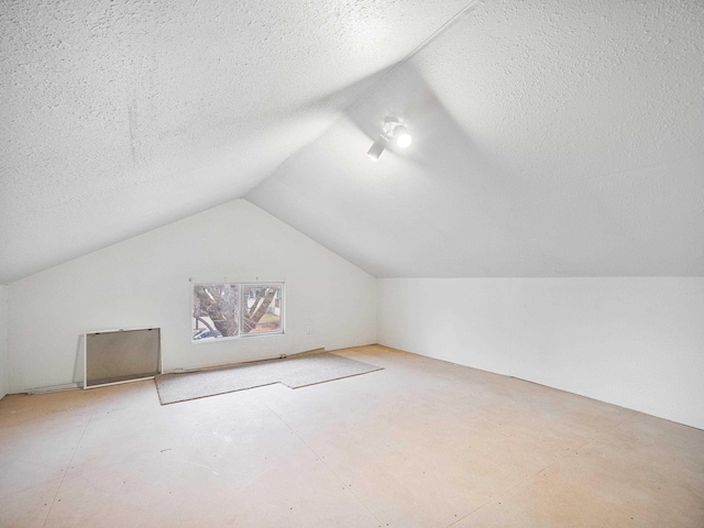 bonus room with a textured ceiling and vaulted ceiling