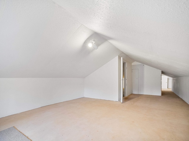 additional living space with vaulted ceiling and a textured ceiling