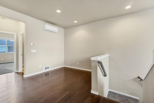 spare room with dark wood-type flooring and a wall mounted AC