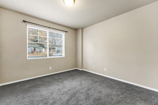 empty room featuring dark carpet and a textured ceiling