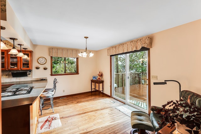 dining room with an inviting chandelier, a wealth of natural light, and light hardwood / wood-style flooring