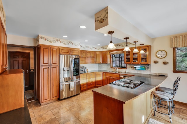 kitchen with sink, stainless steel appliances, tasteful backsplash, kitchen peninsula, and a breakfast bar area