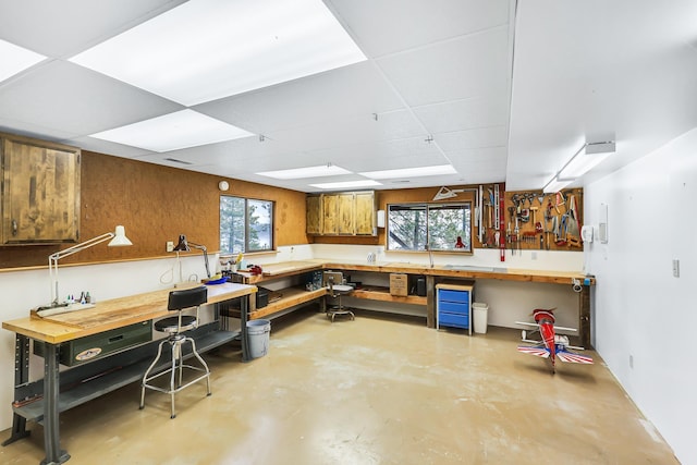 basement featuring a workshop area, a paneled ceiling, and wood walls