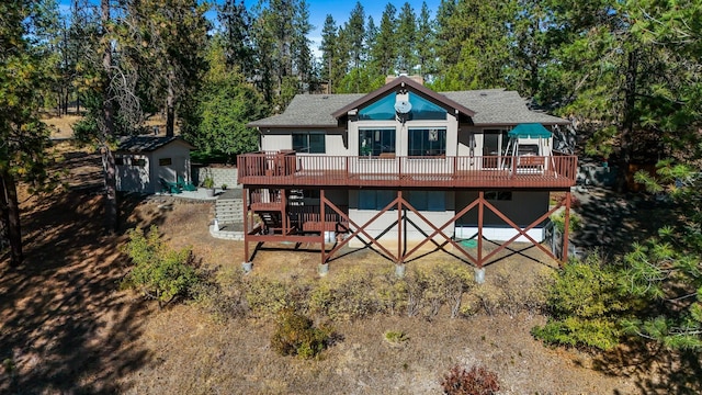 back of property featuring a deck and a storage unit