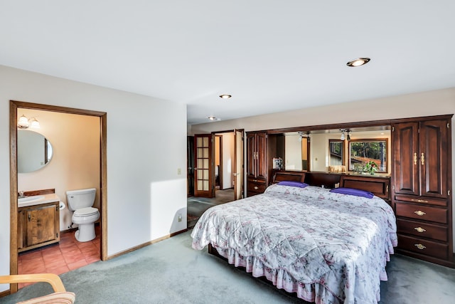 bedroom with connected bathroom, light carpet, and sink