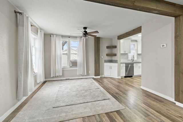 unfurnished living room featuring ceiling fan, light hardwood / wood-style floors, and sink