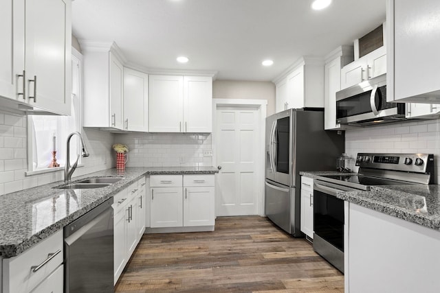 kitchen with dark hardwood / wood-style flooring, stainless steel appliances, sink, dark stone countertops, and white cabinets