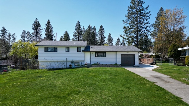 split level home featuring a garage, a front yard, concrete driveway, and fence
