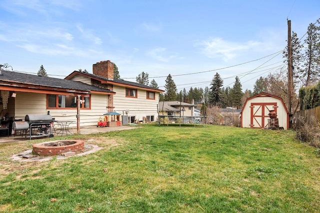 view of yard featuring an outdoor fire pit, a storage unit, and a patio