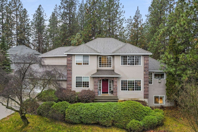 view of front of home featuring a shingled roof and brick siding