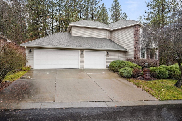 view of front of house with a garage, driveway, and roof with shingles