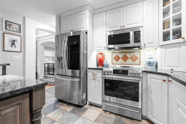 kitchen with decorative backsplash, white cabinetry, appliances with stainless steel finishes, and dark stone counters