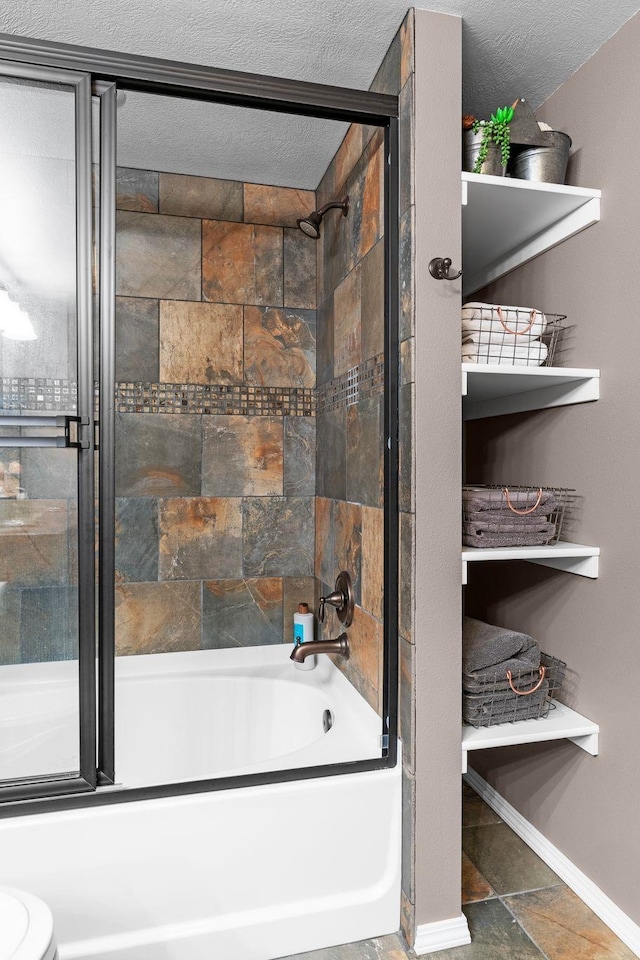 bathroom featuring enclosed tub / shower combo, a textured ceiling, and toilet