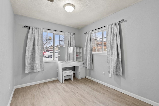 home office with a textured ceiling and light wood-type flooring